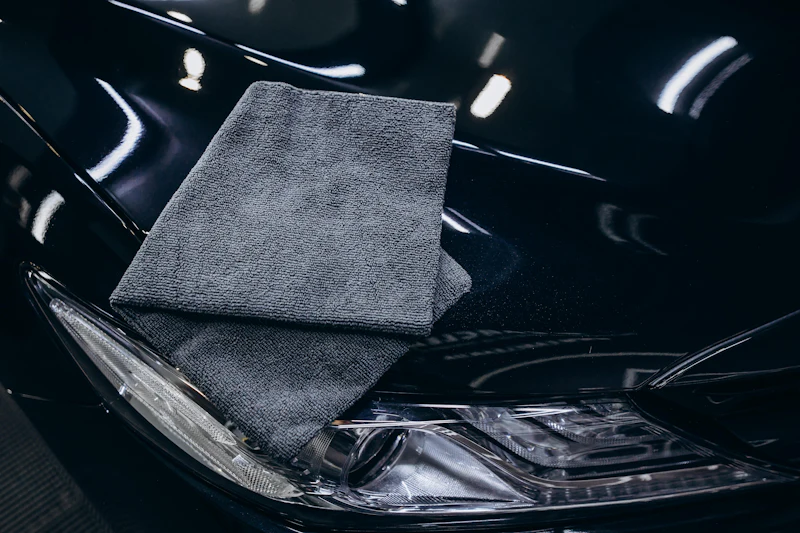 Graues Mikrofasertuch auf einer glänzenden schwarzen Motorhaube