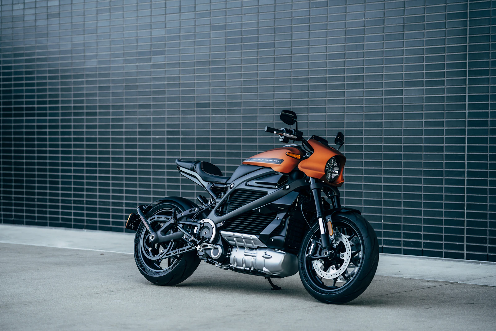Schwarz-oranges Motorrad vor einer dunklen Fliesenwand
